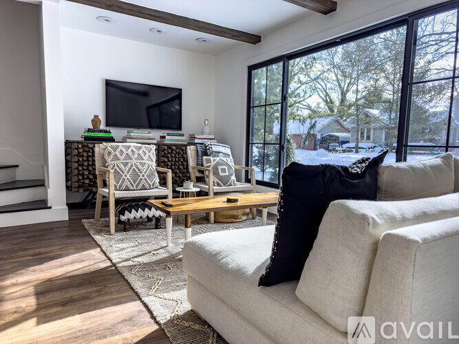 A living room with a white couch and a television on the wall.