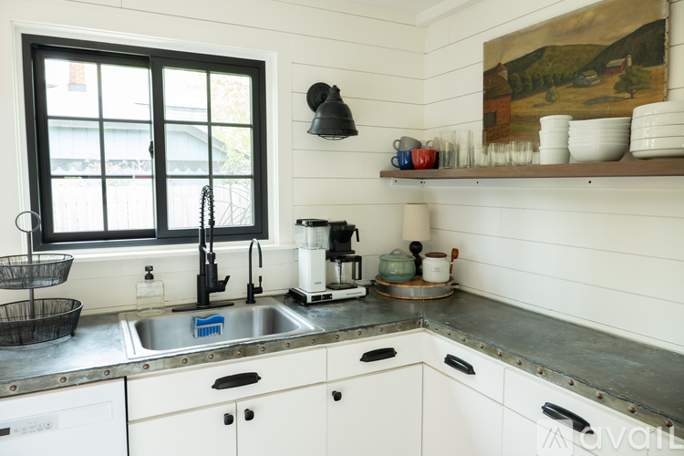 A kitchen with a sink, a window, and a painting on the wall.