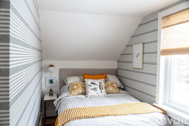 A bedroom with a bed, pillows, and a lamp.