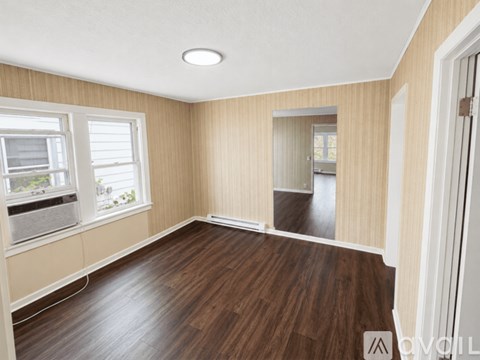 A room with wooden floors and a window with blinds.