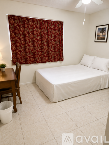 A bedroom with a bed, desk, and window with red curtains.