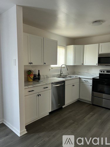 A kitchen with white cabinets and a wooden floor.