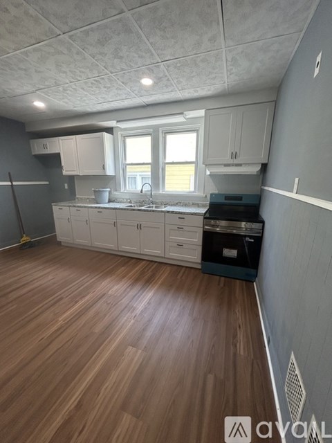 A kitchen with wooden floors and white cabinets.