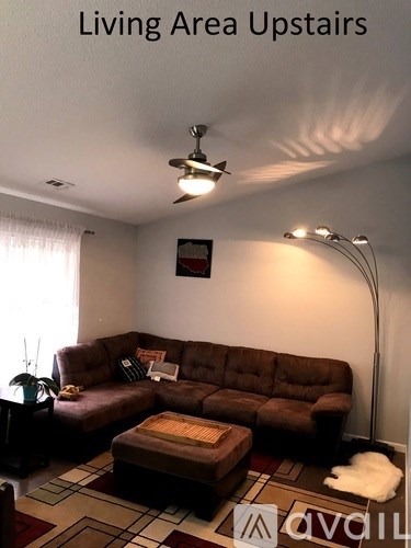 A living room with a brown couch and a rug.