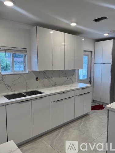 A kitchen with white cabinets and marble countertops.