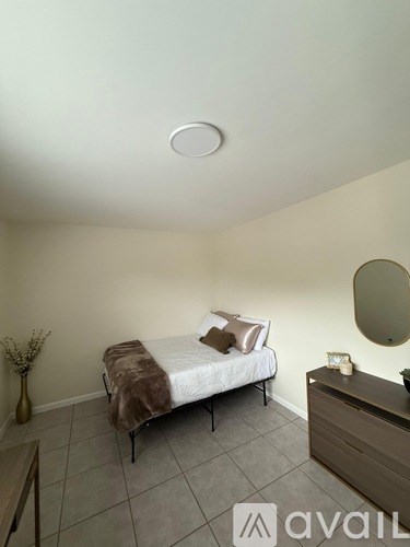A bedroom with a bed, nightstand, and mirror.