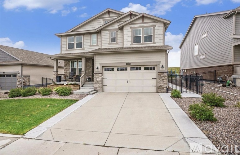 A two-story house with a garage is surrounded by a fence and has a driveway leading to the garage.