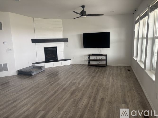 A spacious living room with a fireplace and a television mounted on the wall.
