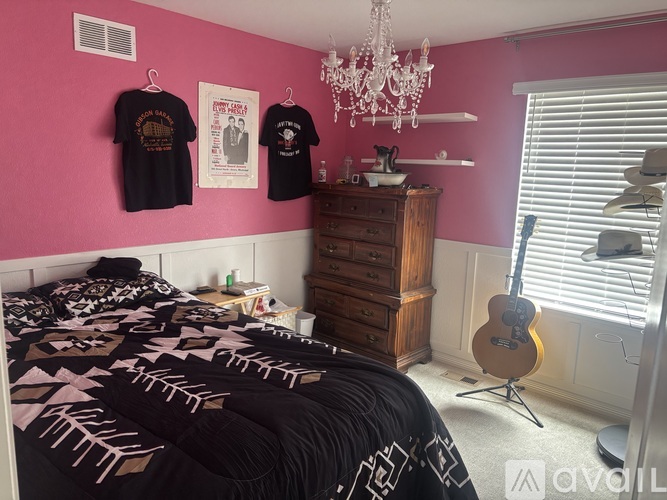 A bedroom with a guitar and two t-shirts hanging on the wall.