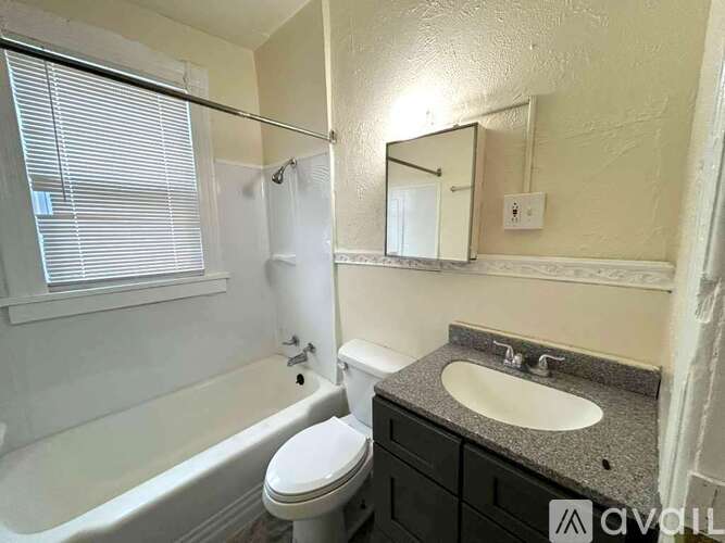 A bathroom with a white toilet, sink, and bathtub.