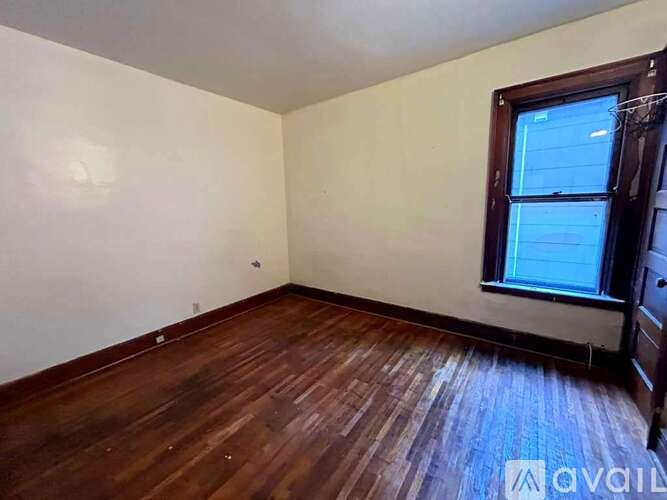 A room with wooden flooring and a window.