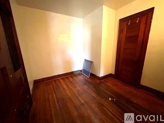 A room with wooden floors and a door on the right side.