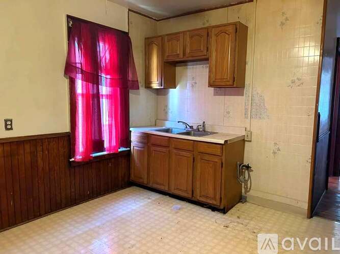 A kitchen with wooden cabinets and a red curtain.