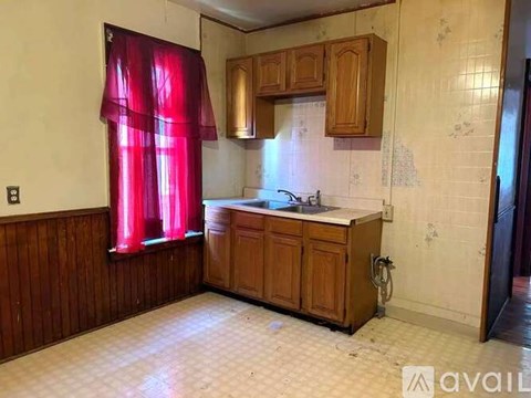 A kitchen with wooden cabinets and a red curtain.