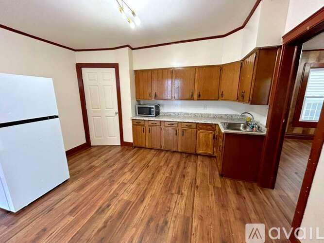 A kitchen with wooden floors and a white refrigerator.