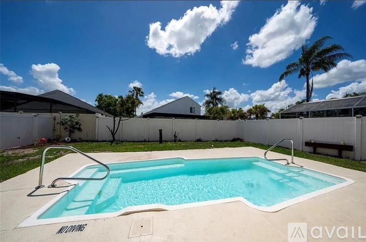 A swimming pool surrounded by a fence and trees.