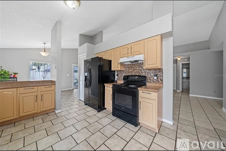 A kitchen with a black refrigerator and stove top oven.