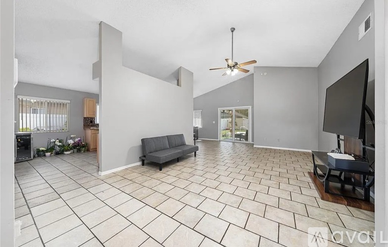 A spacious living room with a grey sofa and a ceiling fan.
