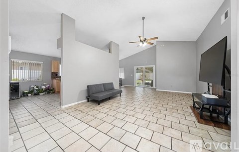 A spacious living room with a grey sofa and a ceiling fan.