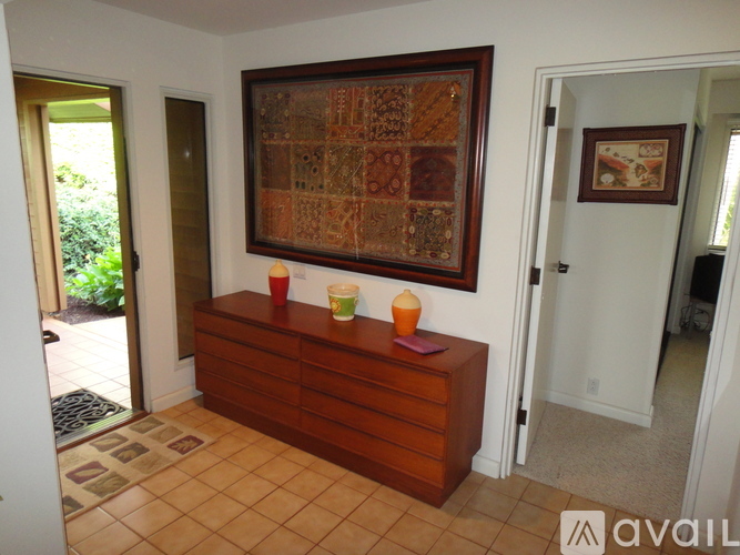 A brown wooden table with a red vase and two orange pumpkins on it.