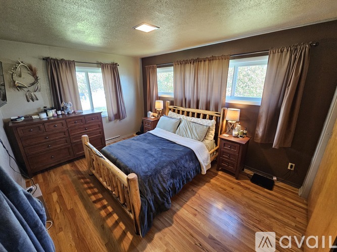 A bedroom with a bed, nightstands, and a window with curtains.
