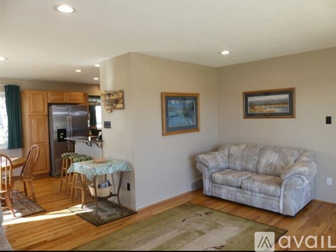 A living room with a couch, a dining table with chairs, and a refrigerator.