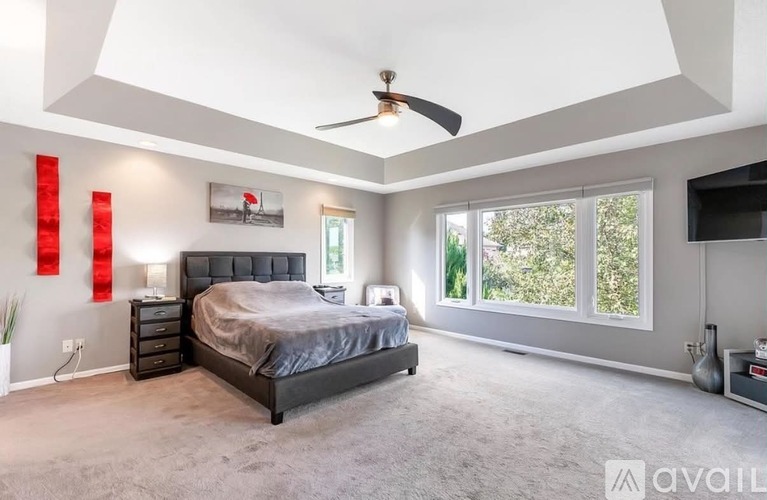A bedroom with a large bed and a ceiling fan.