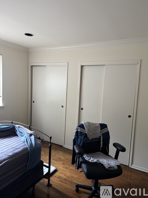 A bedroom with a bed, chair and two doors.