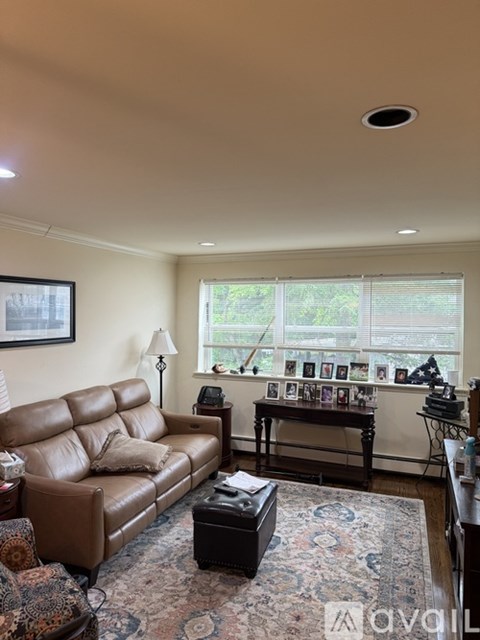 A living room with a brown leather couch and a rug.