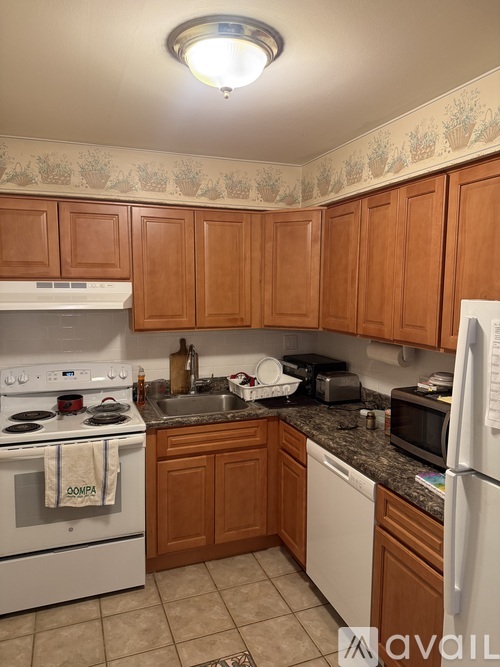 A kitchen with wooden cabinets and a white stove top oven.