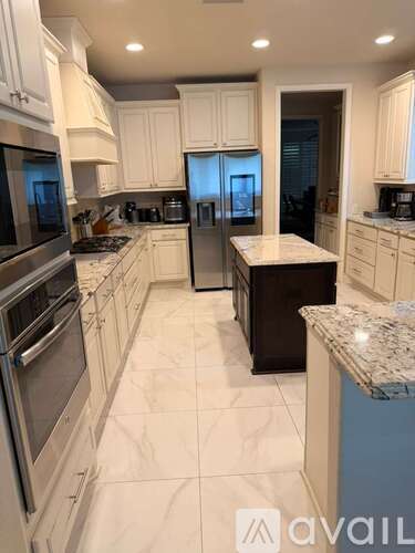 A kitchen with white cabinets and granite countertops.