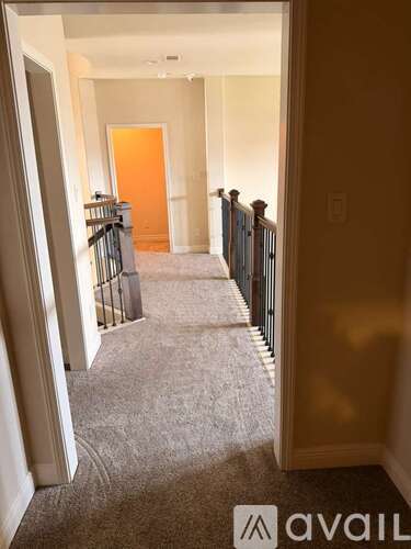 A hallway with a carpeted floor and a railing on the right side.