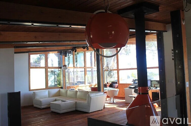 A living room with a white couch and a red light hanging from the ceiling.