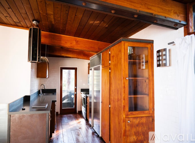 A kitchen with wooden cabinets and a black fridge.