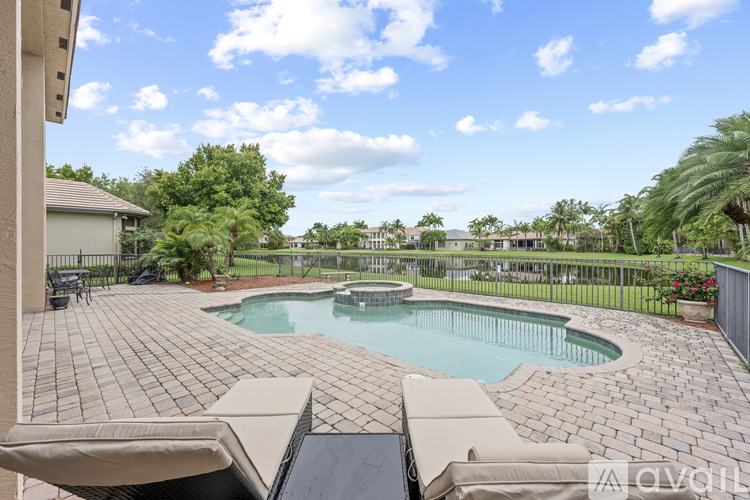 A pool surrounded by a brick patio and a black metal fence.