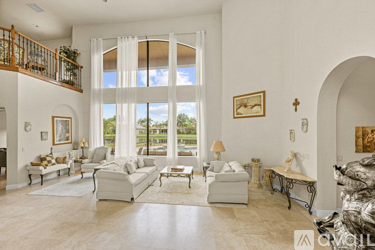 A living room with a white sofa set and a large window.