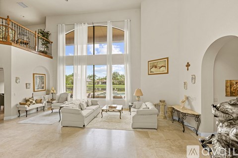 A living room with a white sofa set and a large window.