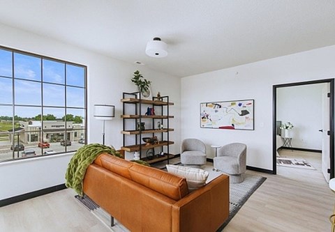 A living room with a brown couch and a green blanket.
