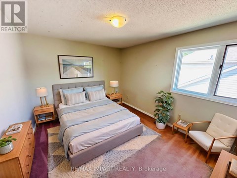 A bedroom with a bed, chair, and window.
