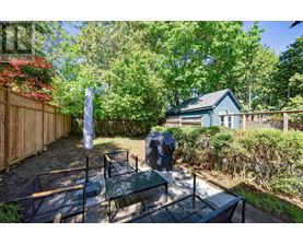 A backyard with a table and chairs and a blue house in the background.