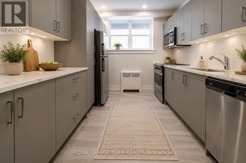 A well-lit, modern kitchen with stainless steel appliances and light grey cabinets.