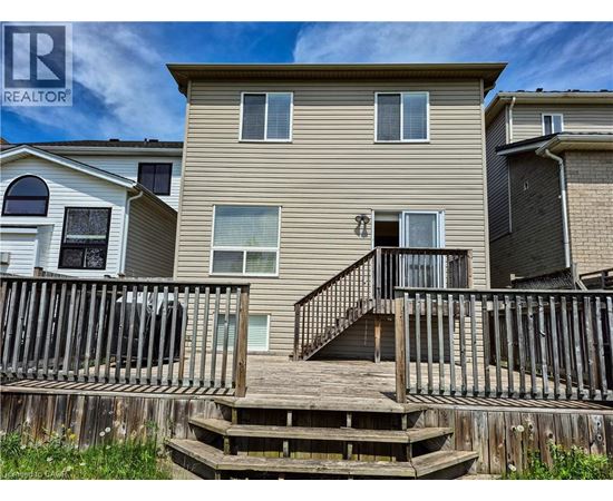 A beige two-story house with a deck in front.