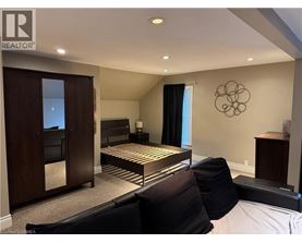 A bedroom with a bed, a chair, and a cabinet.