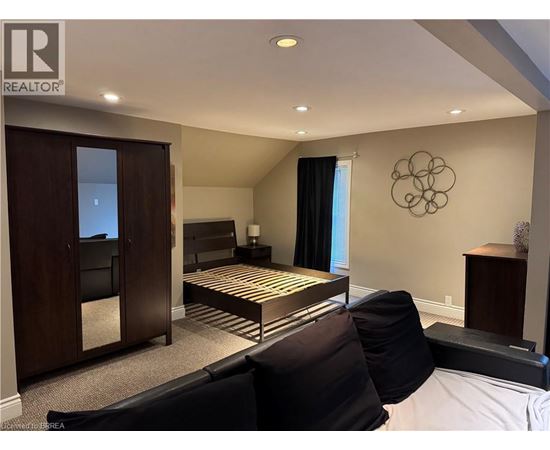 A bedroom with a bed, a chair, and a cabinet.
