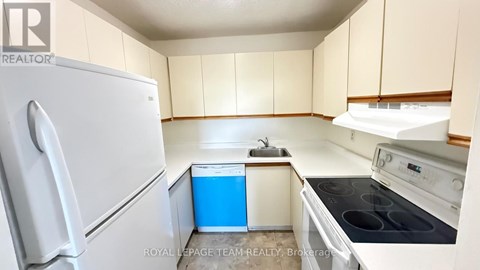 A white refrigerator is in a kitchen with beige cabinets.