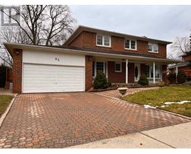 A brick house with a white garage door and a driveway made of bricks.
