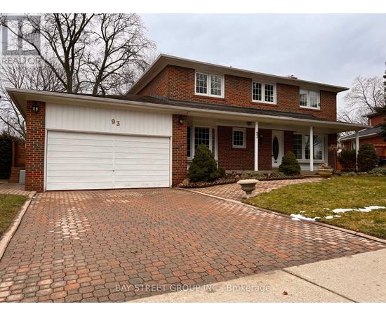 A brick house with a white garage door and a driveway made of bricks.