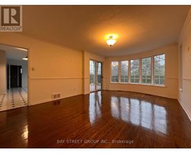 A spacious room with wooden floors and large windows.