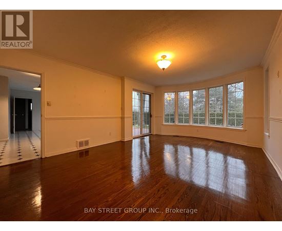 A spacious room with wooden floors and large windows.
