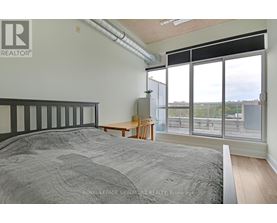 A bedroom with a large bed and a view of the outside through the windows.
